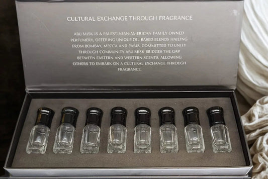Set of small glass bottles with black caps in a gray box on a textured surface.